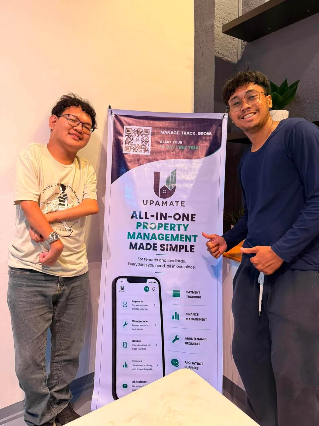Daniel and a teammate beside the UPAMATE banner: all-in-one property management made simple
